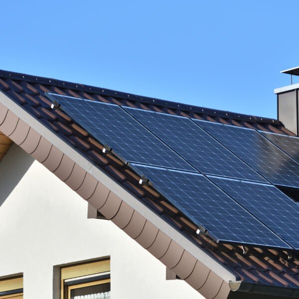 Solar panels installed on the roof of a house with tiles in Europe against the background of a blue sky.
